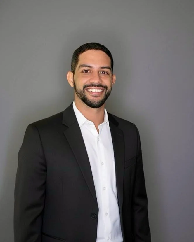 Daniel Falcão sorrindo, de blazer escuro e camisa branca